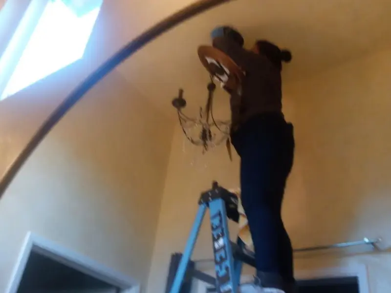 Electrician installing a chandelier in a Freetown residence